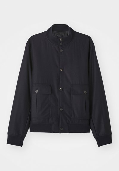 Μπλε ναυτικού σακάκι από μαλακό ύφασμα, με ψηλό γιακά, μπροστινή κλείσιμο με κουμπιά, δύο τσέπες στο στήθος και ριμπ στο κάτω μέρος και τα μανίκια.