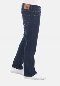 Jeans de mezclilla azul para hombre con corte recto, que cuentan con una etiqueta de cuero marrón en la cintura y costuras en tono beige en las costuras y bolsillos.
