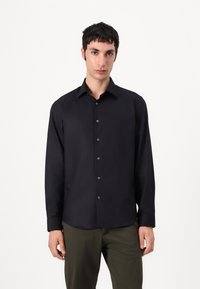 Black long-sleeve shirt featuring a button-down front, classic collar, and smooth texture, worn with olive green pants.