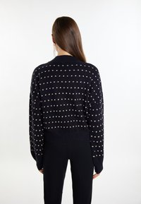Pulover tricotat navy cu o croială lejer�ă, având motive crem cu buline, guler rotund și margine elastică. Purtați-l cu pantaloni negri.