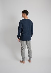 Marine gestreepte longsleeve top met ronde hals, gecombineerd met lichtgrijze joggingbroek. Beide kledingstukken hebben een relaxte pasvorm met geribbelde manchetten.