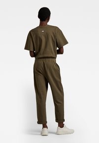 Kaki tvådelad outfit bestående av en lös passform kortärmad topp och byxor med elastisk midja och uppvikta fållar, gjorda i ett lättviktigt material.