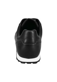 Sneaker in pelle nera con tacco arrotondato, suola bianca e cuciture semplici. Il design è minimalista con una texture liscia.