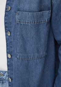 Jeansjack met een enkele borstzak, zilveren knopen en een gestructureerde blauwe stof met zichtbare stiknaaddetails.