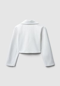 Giacca bianca cropped con una trama a spina di pesce, maniche lunghe e colletto con scollatura a V. La vista posteriore mostra un design pulito e liscio.