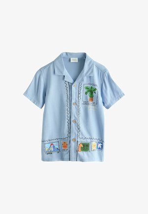 Cămașă albastru deschis cu mânecă scurtă și nasturi, cu imprimeuri colorate tematice de călătorie, inclusiv un palmier, un vulcan și o girafă.