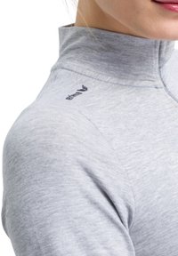 Maglia grigia chiara a mezze zip realizzata in materiale liscio e elasticizzato. Presenta un colletto alto e un logo sulla spalla sinistra.