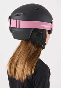 Zwarte skihelm met roze verstelbare band, ventilatiegaten en gevoerde binnenkant. Op de band staat de tekst "SWEDEMOUNT".