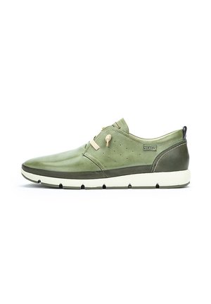 Zapato de cuero verde con punta redondeada, perforaciones en los laterales, suela crema en contraste y cordones elásticos para un ajuste seguro.