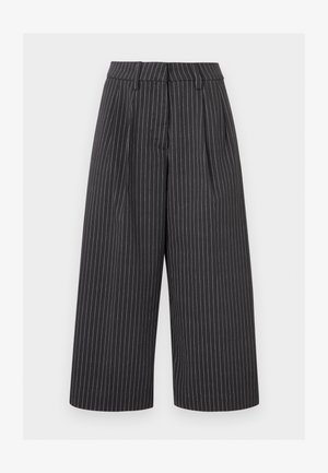 Μαύροι φαρδιά παντελόνια cropped με λευκές κατακόρυφες ρίγες και θηλιές ζώνης σε φωτεινό φόντο.