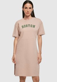 Světle růžová šaty z tričkoviny, vyrobené z jemné bavlny, s kulatým výstřihem a krátkými rukávy. Na přední straně je nápis "BOSTON" v tmavě zeleném písmu.