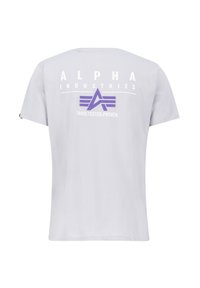 Valge puuvillane T-särk, millel on lilla ja valge "Alpha Industries" logo ning sõnad "KATSETATUD.TÕESTATUD.TEHTUD." seljal.