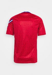 Camiseta deportiva roja con un patrón de texto repetido que dice "PARÍS", cuello azul y un detalle en las mangas con rayas blancas y azules, mostrada desde la parte de atrás.