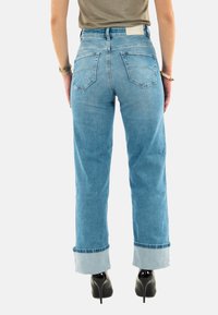 Vaqueros de mezclilla azul claro con un diseño de pierna recta, puños enrollados y dos bolsillos traseros. El material parece suave con un ligero desgastado.