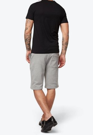 Sort kortærmet t-shirt og grå sweatshorts med en afslappet pasform og sidelommer, parret med sort fodtøj.