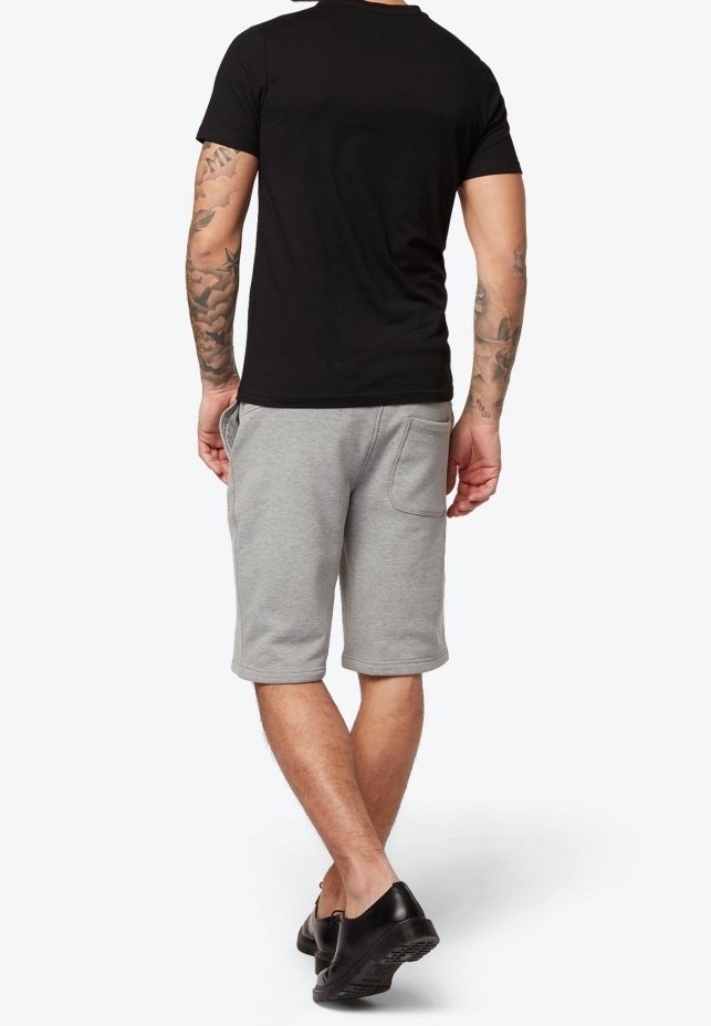 T-shirt noir à manches courtes et shorts en sweat gris, avec une coupe décontractée et des poches latérales, associés à des chaussures noires.