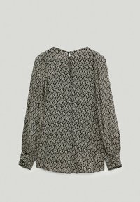 Langärmlige Bluse in Schwarz und Weiß mit geometrischem Muster. Weiches, leichtes Material mit Knopfverschlüssen auf der Rückseite und gerafften Ärmeln.
