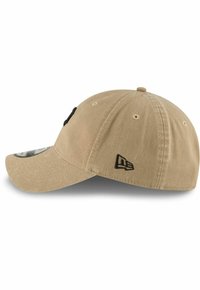 Gorra de algodón beige con visera curvada, que presenta un logo y acentos bordados en negro, diseño estructurado y ojales de ventilación.