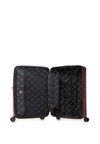 Valise rigide rouge avec des rainures horizontales, ouverte pour révéler un intérieur en tissu noir avec un motif en losange, des sangles et un compartiment zippé.