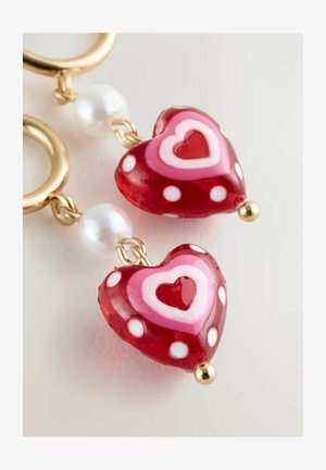 Red and pink heart-shaped earrings with white polka dots, gold hardware, and a pearl bead accent. Glass material with layered designs.
