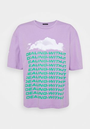 Fliederfarbenes T-Shirt mit kurzen Ärmeln, weißer Wolkengrafik und wiederholtem grünem Text mit der Aufschrift "DEALING-WITH-IT" vertikal auf der Vorderseite.