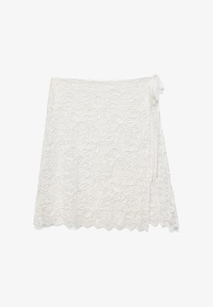 Hvid blonde omslagsnederdel med blomsterbroderi og bølget kant, med bindebånd i siden på en ensfarvet baggrund.