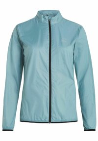 Lyseblå vindjakke lavet af letvægtsmateriale. Har høj krave, fuldlængde lynlås og sorte detaljer langs lynlåsen og manchetterne.