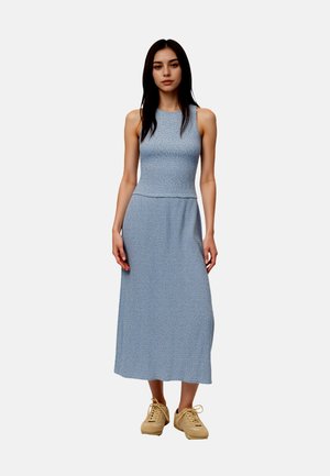 Maxi-jurk in blauw met een gestructureerde stof. Mouwloos met een aansluitend bovenstuk en een vloeiende onderkant. Gecombineerd met beige plateau sneakers.