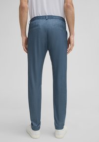 Blauwe, gemarmerde broeken met een trekkoorden taille en twee achterzakken. Draagt met witte sneakers.