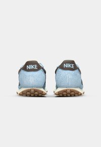 Buty sportowe Nike z miękką cholewką z niebieskiego zamszu, brązowymi akcentami, wyściełanym kołnierzem i teksturowaną gumową podeszwą z widocznym bieżnikiem.