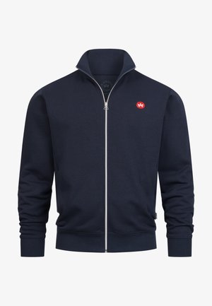 Donkerblauwe sweatvest met rits, gemaakt van zacht stof. Heeft een opstaande kraag, geribbelde boorden en een klein rood logo op de linkerborst.