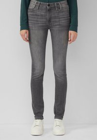 Jean skinny gris avec une légère décoloration et un léger effet de whiskering. Conçu avec une disposition à cinq poches et des accents métalliques à la taille.