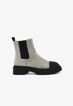 Bottes de cheville texturées argentées avec des panneaux latéraux élastiques noirs, une semelle épaisse noire et un détail de capuchon à clous.