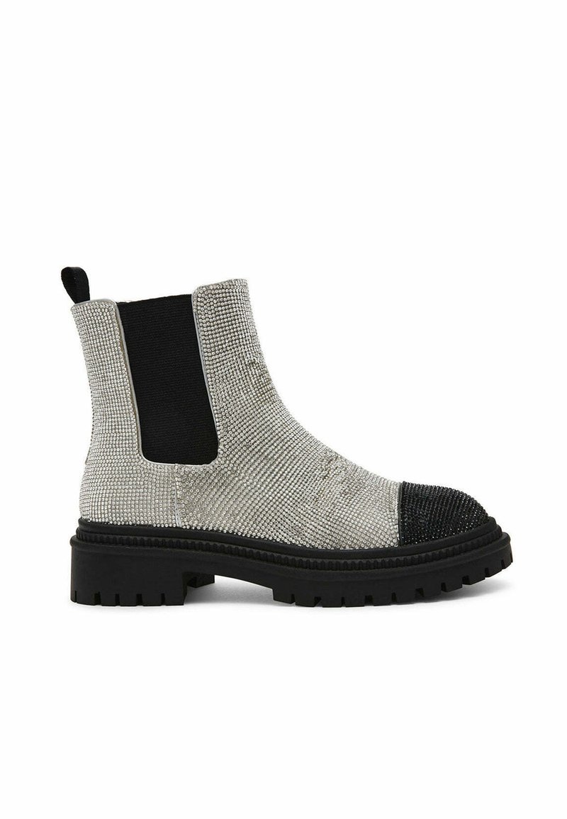 Bottes de cheville texturées argentées avec des panneaux latéraux élastiques noirs, une semelle épaisse noire et un détail de capuchon à clous.