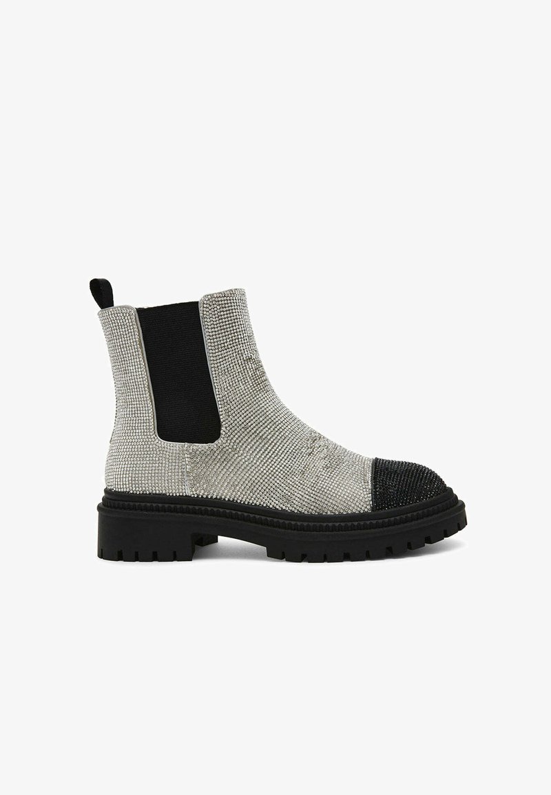 Bottes de cheville texturées argentées avec des panneaux latéraux élastiques noirs, une semelle épaisse noire et un détail de capuchon à clous.