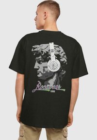 Juodas marškinėliai su klasikinio statulos grafika, dėvinčios ausines. Po ja esančiuose raštuose išsiskiriantis tekstas "Rocawear 1999" spalvingu, šriftu.