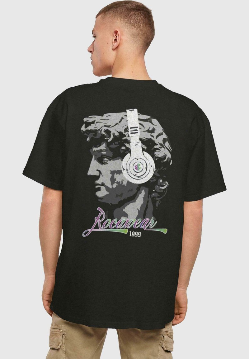 Juodas marškinėliai su klasikinio statulos grafika, dėvinčios ausines. Po ja esančiuose raštuose išsiskiriantis tekstas "Rocawear 1999" spalvingu, šriftu.
