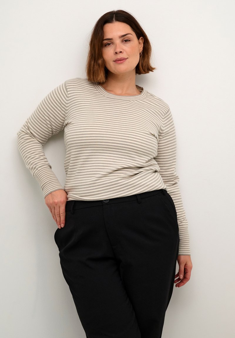 Striped long-sleeve top in beige and off-white, featuring a round neckline and ribbed cuffs, paired with black tailored trousers.