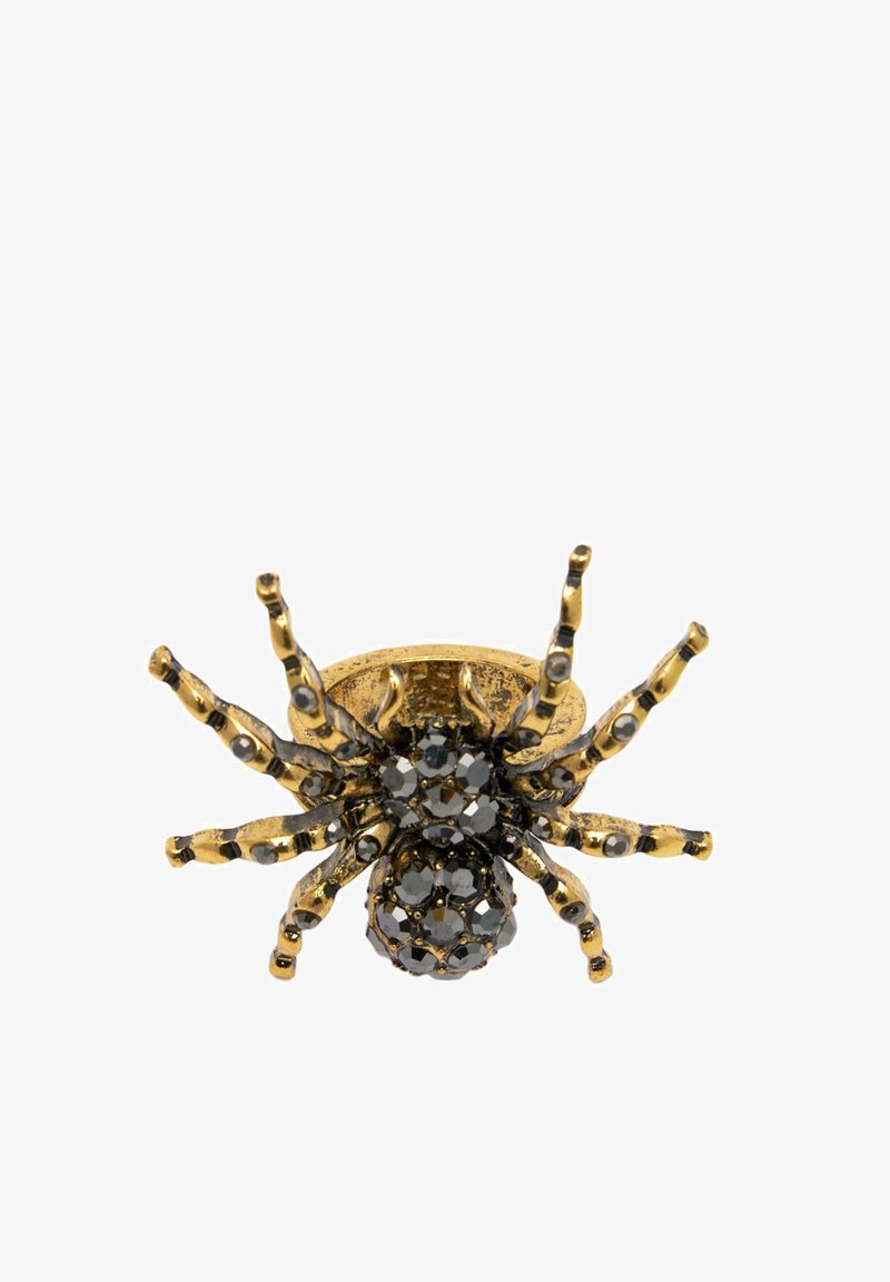 Anello a forma di ragno in tonalità oro con embellishments in cristallo nero sul corpo e sulle zampe, caratterizzato da un design testurizzato e da dettagli intricati.