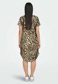 Leopardmönstrad klänning med korta ärmar, rundad nederkant och avslappnad passform; tillverkad av mjukt tyg. Bärs med vita sneakers.