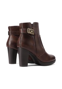 Stivaletti in pelle marrone con tacco, punta rotonda, elastico laterale e un elegante dettaglio in oro sulla caviglia esterna.