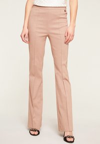 Pantaloni flare rosa chiaro con una leggera lucentezza, caratterizzati da una vita aderente, cuciture laterali e un accento metallizzato in vita.