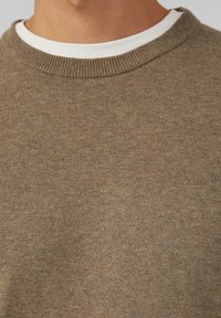 Brązowy sweter z dzianiny z okrągłym dekoltem, z białą wewnętrzną warstwą. Dyskretny logo s.Oliver na dolnej części. Miękka tekstura.