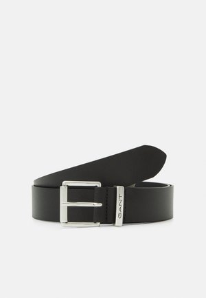 Curea din piele neagră cu o prindere din metal argintiu și detalii gravate ale mărcii. Textură plată și netedă, cu un design clasic și linii curate.