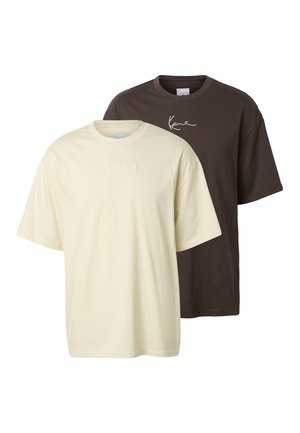 Dve jednoduché tričká s krátkym rukávom a okrúhlym výstrihom, jedno krémové a jedno tmavohnedé, každé s malým bielym logom v písanom štýle na hrudi.