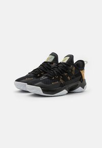 Czarne sportowe sneakersy z siateczkową cholewką, złotymi akcentami i logo, teksturowanymi czarnymi nakładkami oraz białą gumową podeszwą z wzorem.