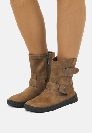 Botas de tobillo de ante marrón con punta redondeada, cierre de cremallera en el lateral y dos hebillas ajustables en la parte superior. Suela de goma para mayor tracción.