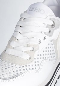 Sneaker bianca con accenti argentati, caratterizzata da un pannello in suede testurizzato, dettagli perforati e lacci piatti bianchi. Il logo del marchio è impresso in argento.
