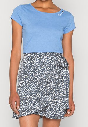 Jasnoniebieska koszulka z krótkim rękawem i dekoltem w serek, zestawiona z granatową spódnicą w białe kwiatowe wzory i wiązaniem z boku.