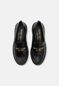 Čierne kožené loafers s lesklým povrchom, so zlatým logom na remienku a textúrovanou gumovou podrážkou. Klasický dizajn.